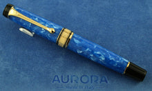 Load image into Gallery viewer, Front view of the Fountain Pen with the cap on. Placed on top of the blue felt presentation box. The pen has a white and blue marbled body with gold trims. The top of the cap and the bottom of the pen are made of black resin.