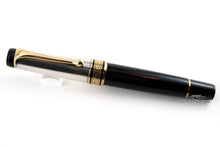 Load image into Gallery viewer, Front view of the pen on a white background. The body is made of black resin with a small golden ring. The cap is silver with gold vermeil accents.