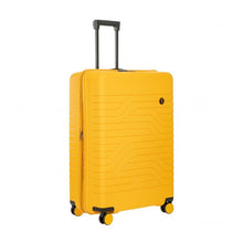 Load image into Gallery viewer, Front angled view of the mango yellow hard shell suitcase with black trims. The front panel has a wave lines design and a small circular black logo at the top right.