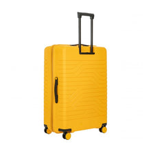 Load image into Gallery viewer, Angled back view of the mango yellow suitcase with black trims. The left side has a black handle for easy grabbing. The telescopic handle is pulled up.