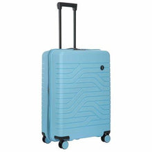 Load image into Gallery viewer, Angled front view of the light blue, hard shelled suitcase with black trims. it has a textured wave lines design, and a small circular black logo on the top right.