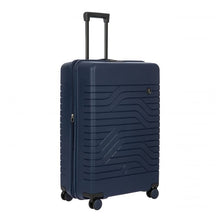Load image into Gallery viewer, A matte navy blue, hard-shell suitcase with a textured wave pattern on the front. It has four spinner wheels, a retractable black handle on top, and a small circular logo with the letters "BV" on the front.