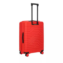 Load image into Gallery viewer, Back angled view of the red hard shell suitcase with black accents. The back panel has a textured design of wave lines, and a handle on the left side.