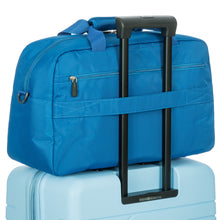 Load image into Gallery viewer, Back view of the duffle bag with the back horizontal strap slid into the telescopic handle of a suitcase.