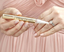 Load image into Gallery viewer, A set of hands holding the Bling Brush for use on a diamond ring. Set on a pink background.