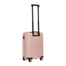 Load image into Gallery viewer, Angled back view of the pearl pink hard shell suitcase with black accents. The back panel has a textured wave lines design. The telescopic handle is pulled up.