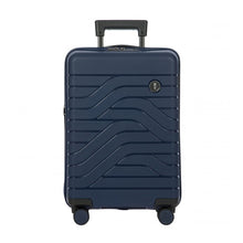 Load image into Gallery viewer, Front view of the navy blue hard shell suitcase with black accents. The panel has a textured wave lines design, and a small black circular logo at the top right. The telescopic handle is partly pulled up.
