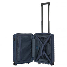 Load image into Gallery viewer, Interior view of the navy blue hard shell suitcase with black accents. The fabric lining is navy blue. The front panel's side has a zipper-closing compartment. The back panel's side has a set of strips to hold contents in place.