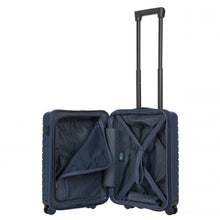 Load image into Gallery viewer, Interior view of the navy blue hard shell suitcase with black accents. The fabric lining is navy blue. The front panel's side has a zipper-closing compartment, partly opened. The back panel's side has a set of strips to hold contents in place.