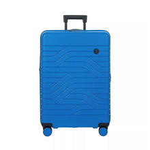 Load image into Gallery viewer, Front view of the electric blue hard shell suitcase with black accents. The panel has a wave lines design and a small black circular logo at the top right. The telescopic handle is partly puled up.
