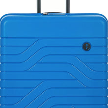 Load image into Gallery viewer, Close up to the top front of the electric blue hard shell suitcase. A small circular logo with the BY initials is at the top right.