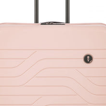 Load image into Gallery viewer, Close up to the front of the pink pearl hard shell suitcase. The wave lines design is visible with the circular black BY logo at the top right.