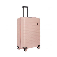 Load image into Gallery viewer, Angled front view of the pearl pink hard shell suitcase with black accents. The front panel has a textured wave lines design, and a small black circular logo at the top right. The telescopic handle is pulled up.
