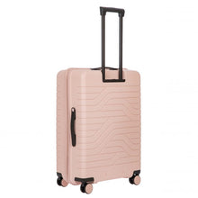 Load image into Gallery viewer, Angled back view of the pearl pink hard shell suitcase with black accents. The back panel has a textured wave lines design. The telescopic handle is pulled up.