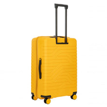 Load image into Gallery viewer, Angled back view of the mango yellow hard shell suitcase with black accents. The back panel has a textured wave lines design. The telescopic handle is pulled up.