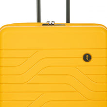 Load image into Gallery viewer, Close up to the top front of the mango yellow hard shell suitcase. The wave lines design is visible with the circular black BY logo at the top right.