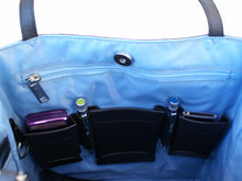 Load image into Gallery viewer, Interior view of the tote bag. It features a blue lining with black organization pockets.
