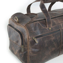 Load image into Gallery viewer, Angled close up to the brown distressed leather duffle bag's side panel