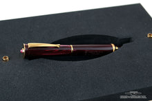 Load image into Gallery viewer, Angled view of the red fountain pen with golden accents in the presentation box slot.