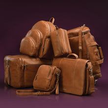 Load image into Gallery viewer, Grouping of 6 different bags from the Dorado Colombian tan Leather Collection. Set on a purple background.