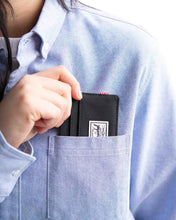Load image into Gallery viewer, Close up to a model sliding the Charlie wallet into their shirt pocket.