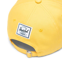 Load image into Gallery viewer, Angled back panel close up to the Lisa Simpson Sylas Cap. It features a sown white Herschel logo tag.
