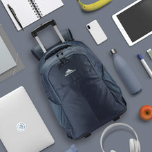 Load image into Gallery viewer, The indigo blue backpack arranged on a gray backpack with electronics, stationery, and food.