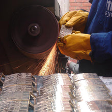 Load image into Gallery viewer, Close up to a pair of hands sanding a piece of metal with machinery.