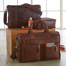 Load image into Gallery viewer, Group shot of three different chocolate-brown leather bags with some accessories. The top one is a messenger bag. The middle one is a shave kit bag. The bottom one is a portfolio bag with compartments.