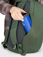 Load image into Gallery viewer, A person tucking a water bottle in the green backpack's side panel pocket.