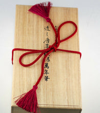 Load image into Gallery viewer, Top view of the wooden presentation box with hand writing on the lid and a red ribbon tying it closed.