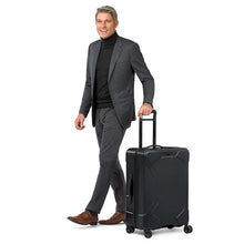 Load image into Gallery viewer, Briggs & Riley Torq Medium Hardside Spinner Luggage - Black
Front Angled View shown wheeled by male model
Dimensions: 27.5"H x 18.5"W x 11.5"D
Weight:         8.9 lbs.