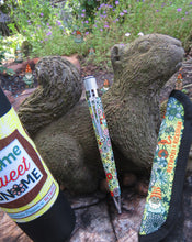 Load image into Gallery viewer, The pen arranged with the gift tube, and Rickshaw sleeve on a garden with a wooden squirrel figure.