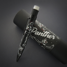 Load image into Gallery viewer, A black mechanical pencil with vintage panther designs leaning on the matching gift tube.