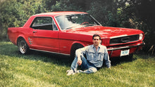 Load image into Gallery viewer, A young man leaning on a red 60s Mustang in a grassy background.
