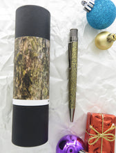 Load image into Gallery viewer, Side view of the pen next to the matching gift tube, arranged with Christmas tree decorations.