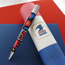 Load image into Gallery viewer, Side view of the 2021 Love Stamp Pen leaning on the gift tube.