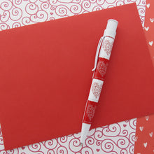 Load image into Gallery viewer, Side view of the 2015 love stamp on a red and white set of decorated prints.