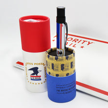 Load image into Gallery viewer, The USPS pen inside the gift tube's bottom portion. The the top portion and a USPS envelope are on the background.