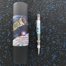 Load image into Gallery viewer, Side view of the pen arranged with the gift tube on a black textured background with blue spots.