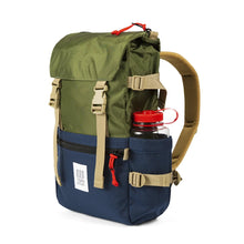 Load image into Gallery viewer, Angled front view of the olive green and navy blue backpack with a water bottle tucked into the side panel's pocket. (Bottle not included).