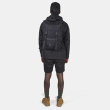 Load image into Gallery viewer, Back view of a young man carrying the black backpack.
