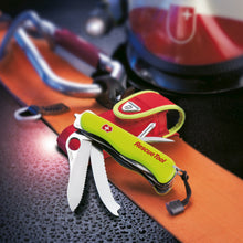 Load image into Gallery viewer, Angled view of the Victorinox Swiss Army Rescue Tool in neon yellow. It is leaning on the included red pouch with the knives fanned out. Other accessories are shown on the back, and are not included.