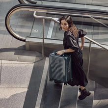 Load image into Gallery viewer, A young woman going up the stairs while holding her navy blue suitcase.