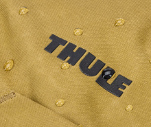 Load image into Gallery viewer, Close up to the Thule log on the front panel with water droplets on the fabric, featuring the waterproof material.