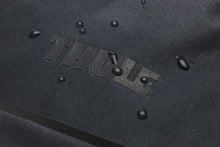 Load image into Gallery viewer, Close up of the Thule logo with water drops sprinkled on the fabric, showing the waterproof feature.