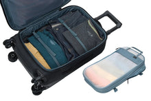 Load image into Gallery viewer, Angled interior view of the suitcase and the organizing bag next to it. Both are filled with clothes.