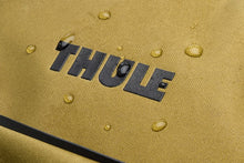 Load image into Gallery viewer, Close up to the Thule logo with water droplets sprayed on it, featuring the fabric's waterproof material.