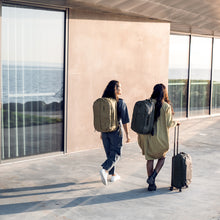 Load image into Gallery viewer, Two women walking whie carrying Thule backpacks and a suitcase.