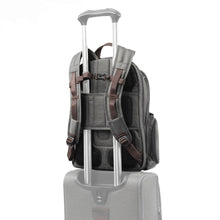 Load image into Gallery viewer, Back panel view of the gray backpack showing the attachment strap holding it to the extended handle of a suitcase.